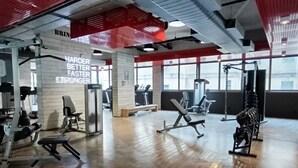 Ein Fitnessstudio mit Trainingsgeräten, motivierenden Sprüchen an der Wand und großen Fenstern.