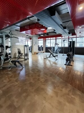 Ein Fitnessstudio mit Trainingsgeräten, motivierenden Sprüchen an der Wand und großen Fenstern.