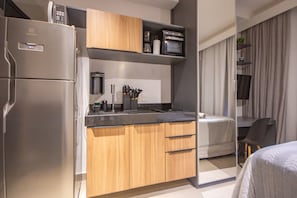 Eine kleine Küchenzeile mit Kühlschrank, Mikrowelle und Kaffeemaschine.
