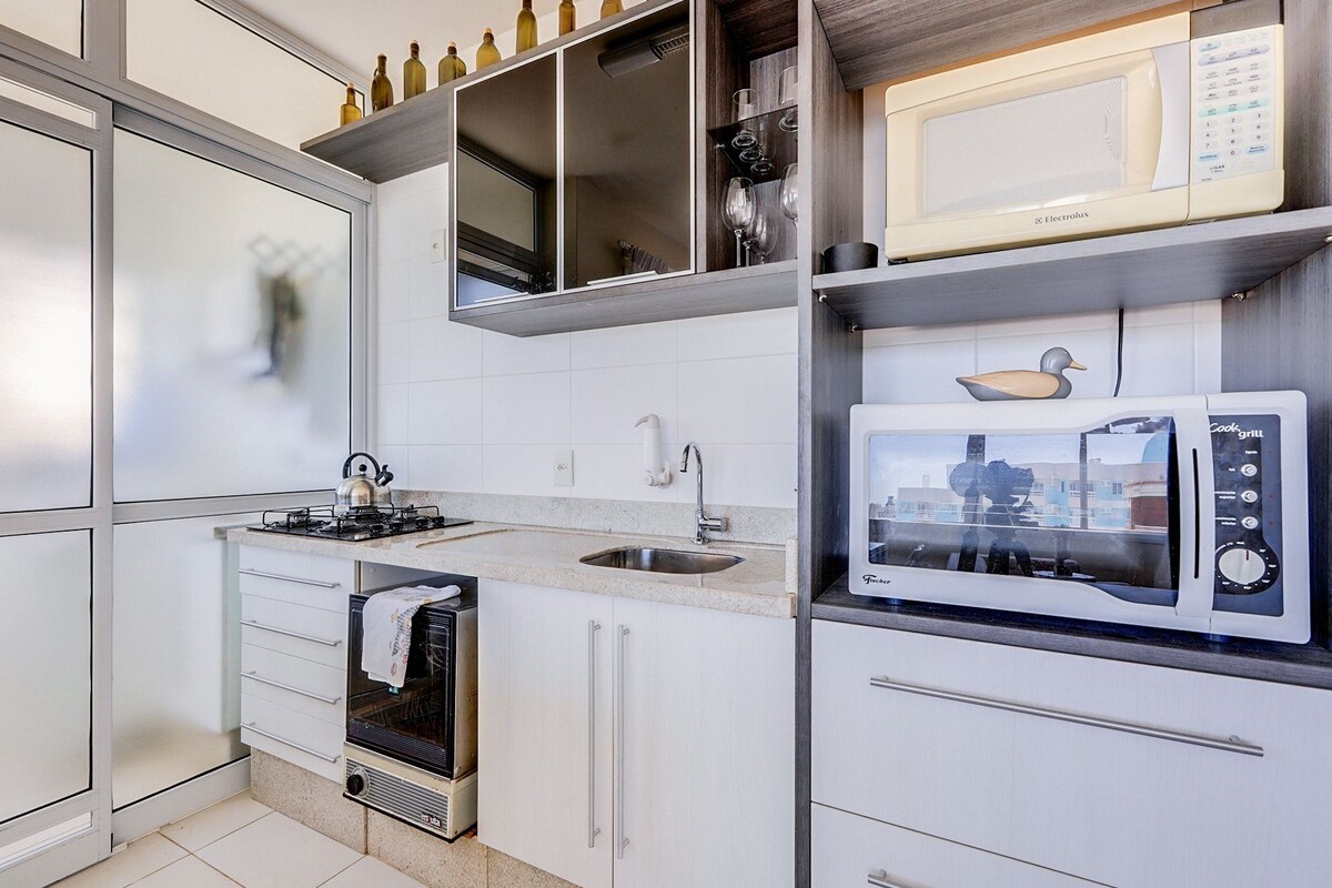 A compact kitchen with a gas stove, a built-in oven, a microwave, and a sink.