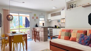 A compact living space with a dining area, kitchenette, and a sofa. - Residencial com piscina (Florianópolis)