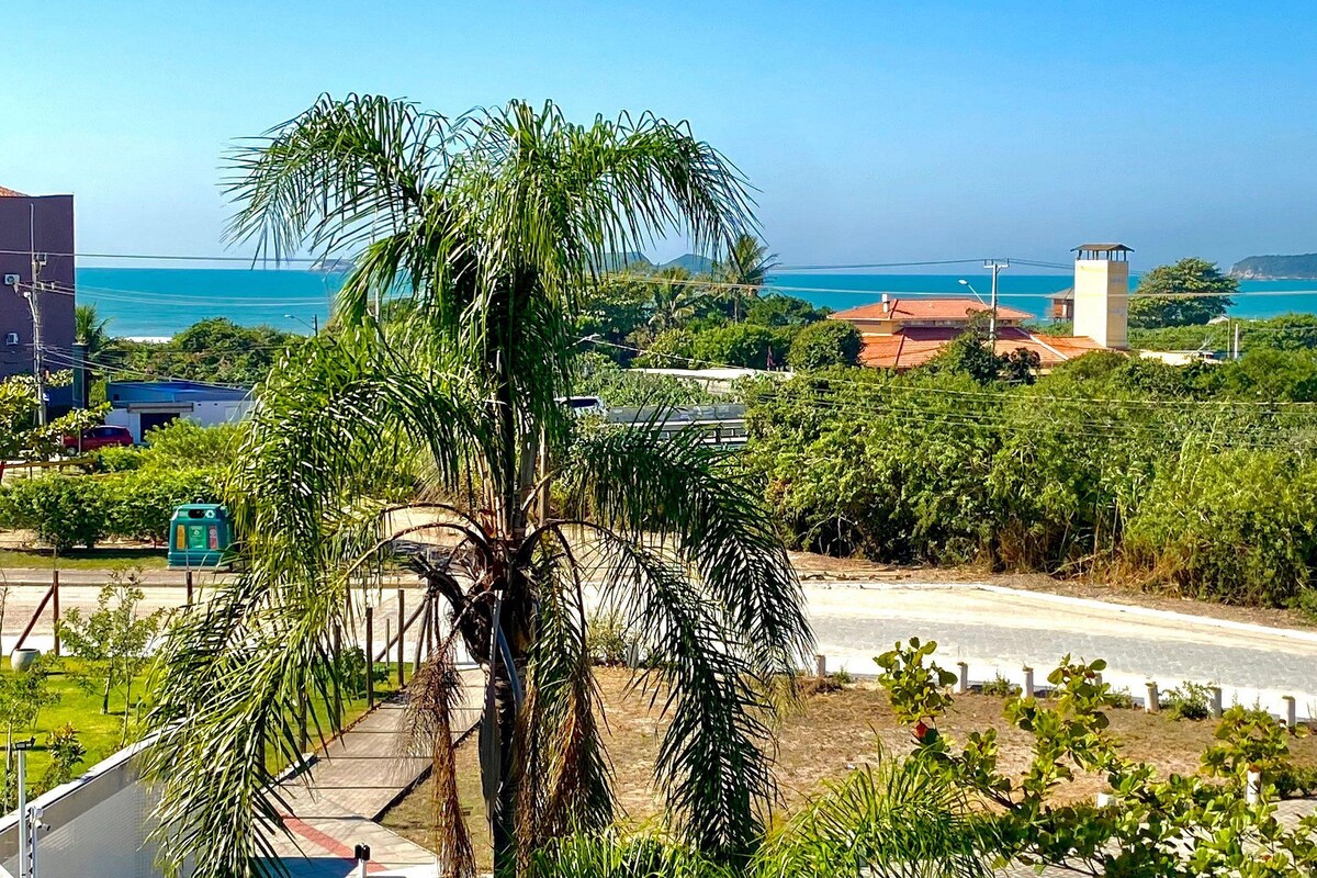 A coastal view with a road, greenery, and buildings.