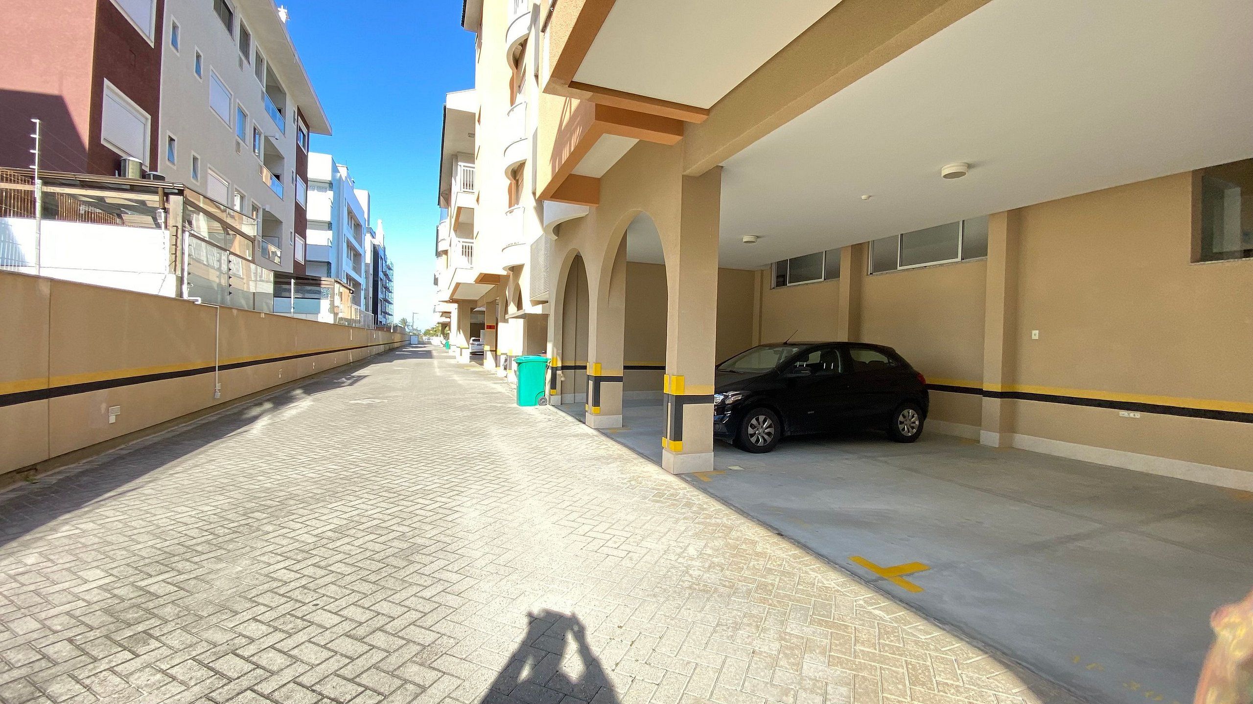 Un estacionamiento con un coche dentro, cielo despejado y edificios al fondo.