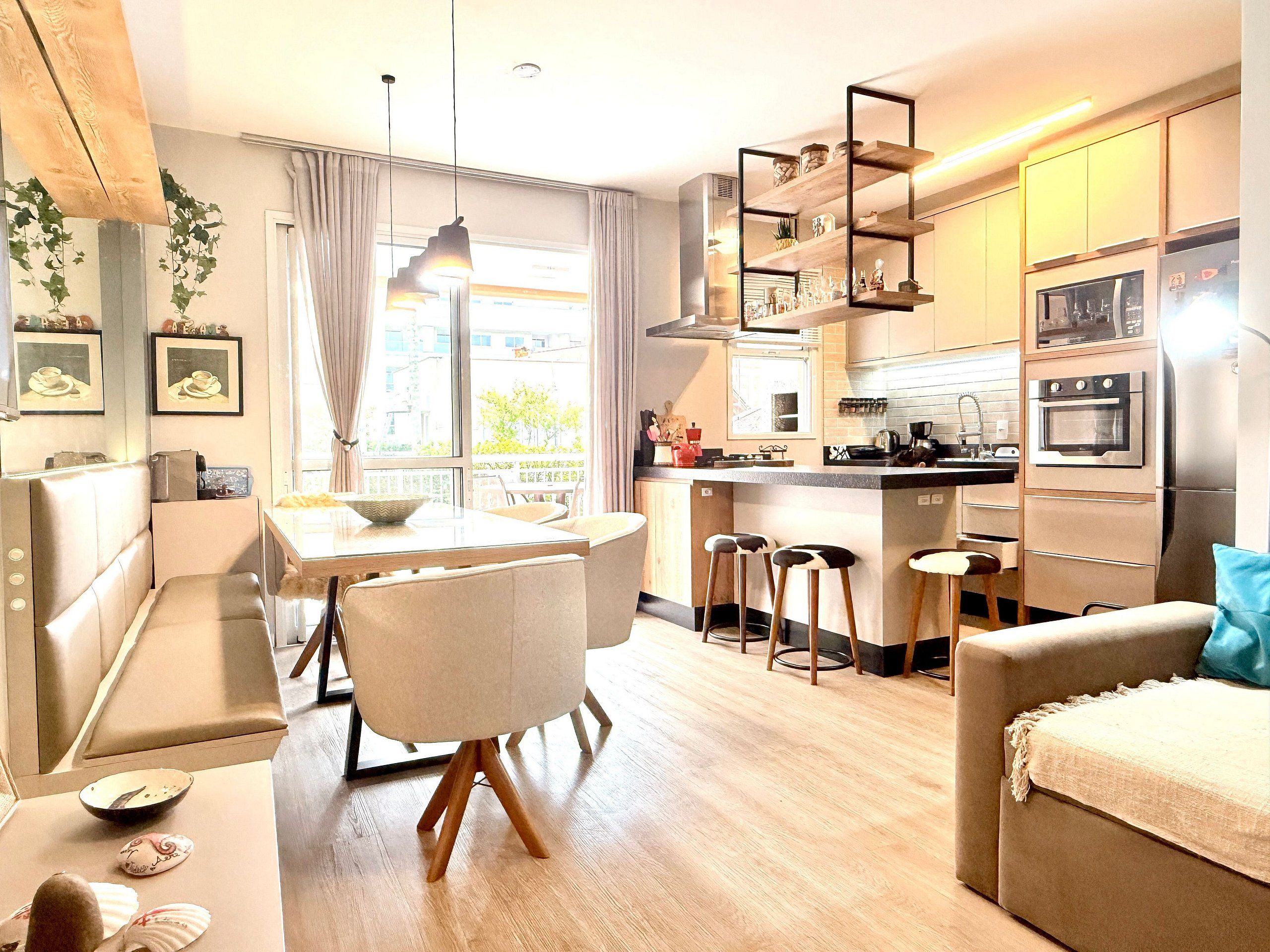 Et moderne køkken med en central ø, barstole og et spiseområde med bord og stole.