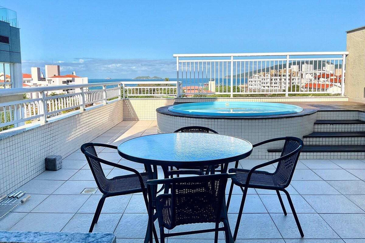 A rooftop terrace with a hot tub, a round table, and four chairs.