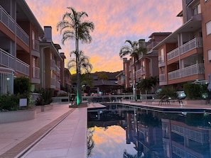 Un edificio residencial con balcones, piscina y palmeras.