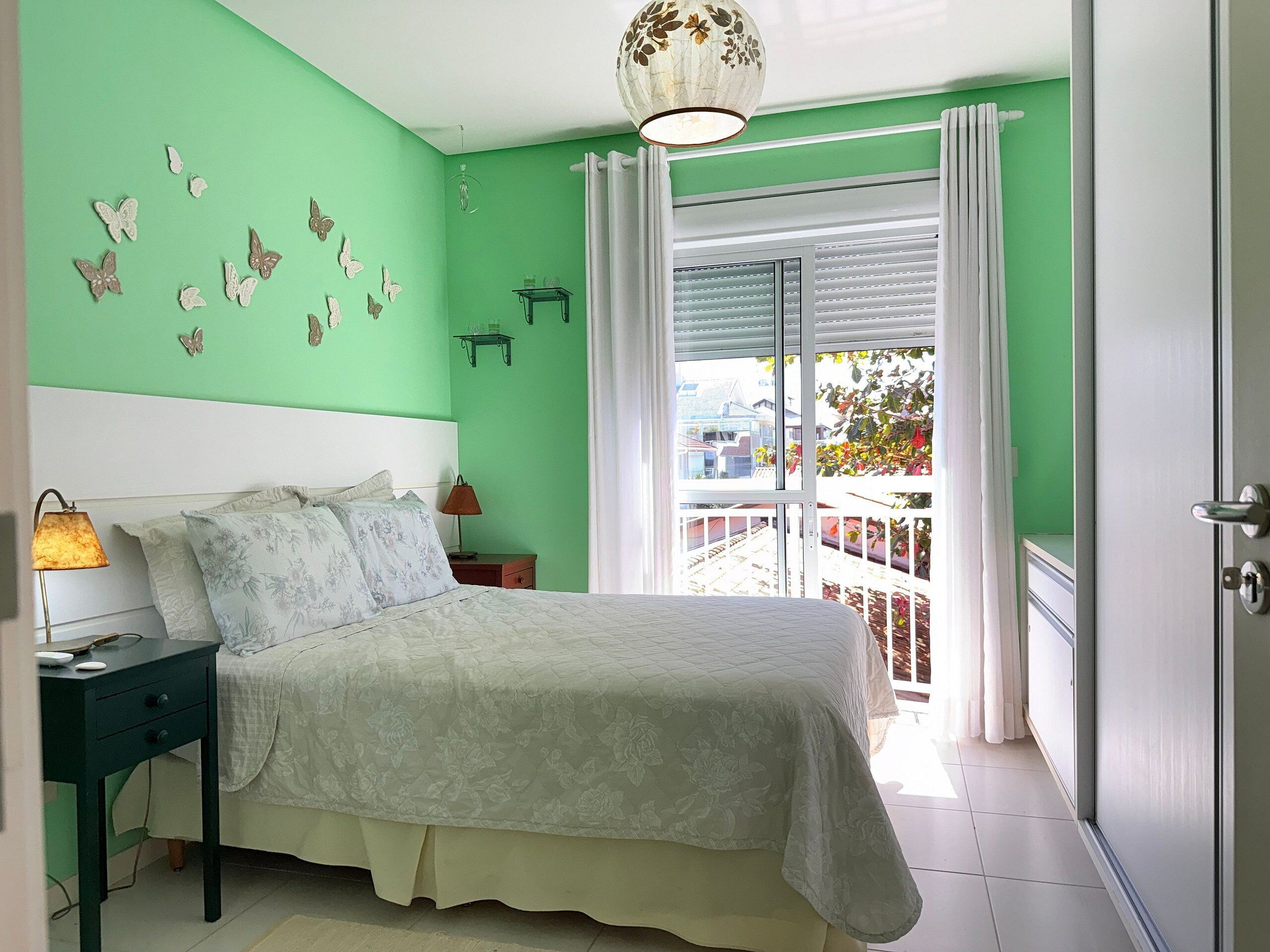 A bedroom with a bed, bedside tables, a window with curtains, and a view of the outside.