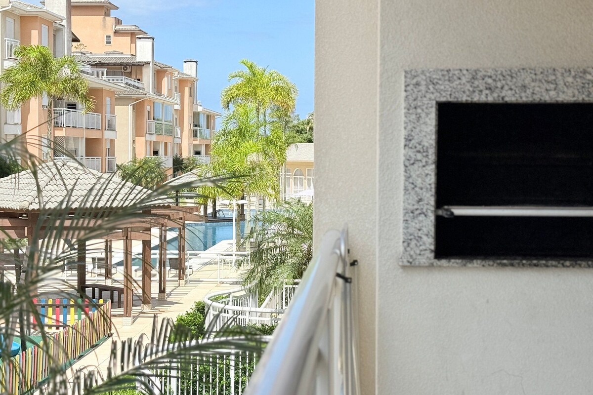 A residential building with balconies, a swimming pool, and a view of other buildings.
