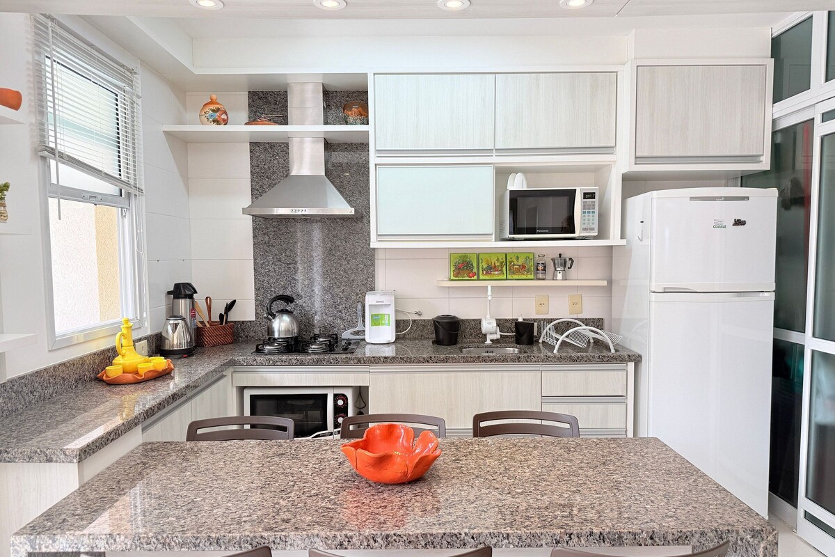 A modern kitchen with granite countertops, a stainless steel kettle, a coffee maker, and a microwave.