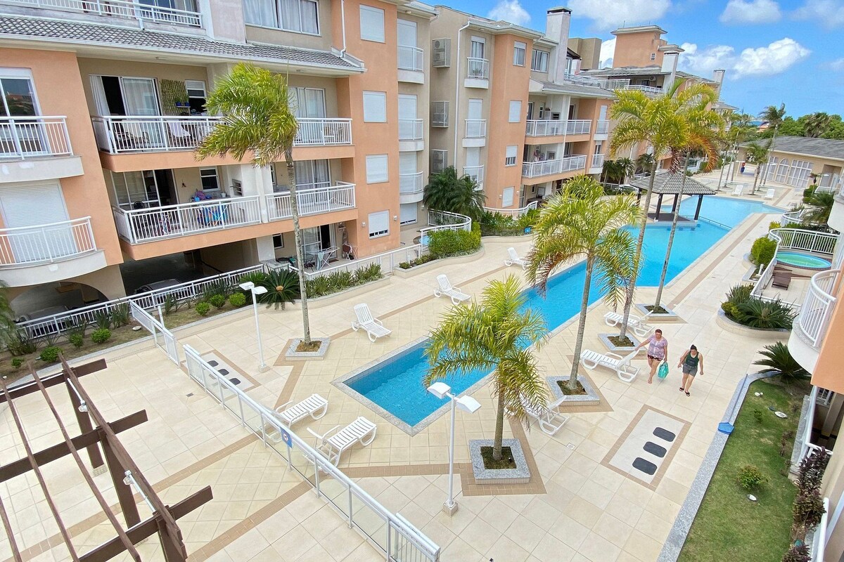 A multi-story hotel with balconies, a swimming pool, and outdoor seating areas.