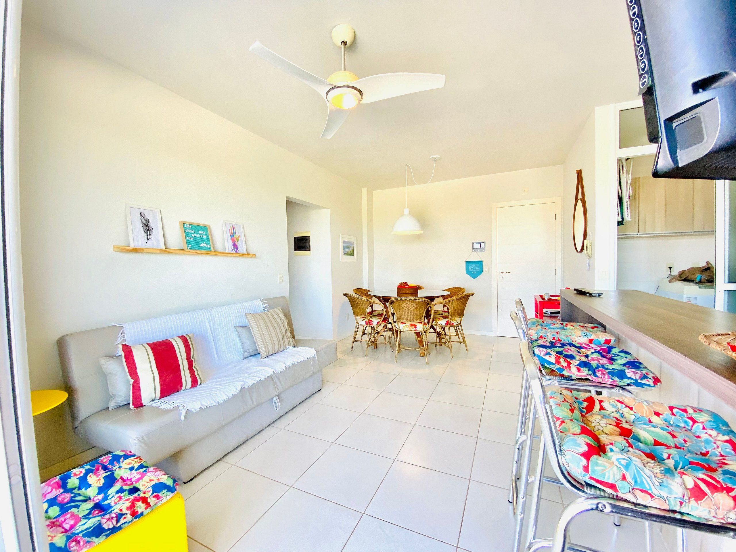 A living room with a sofa, dining table, chairs, and a TV.
