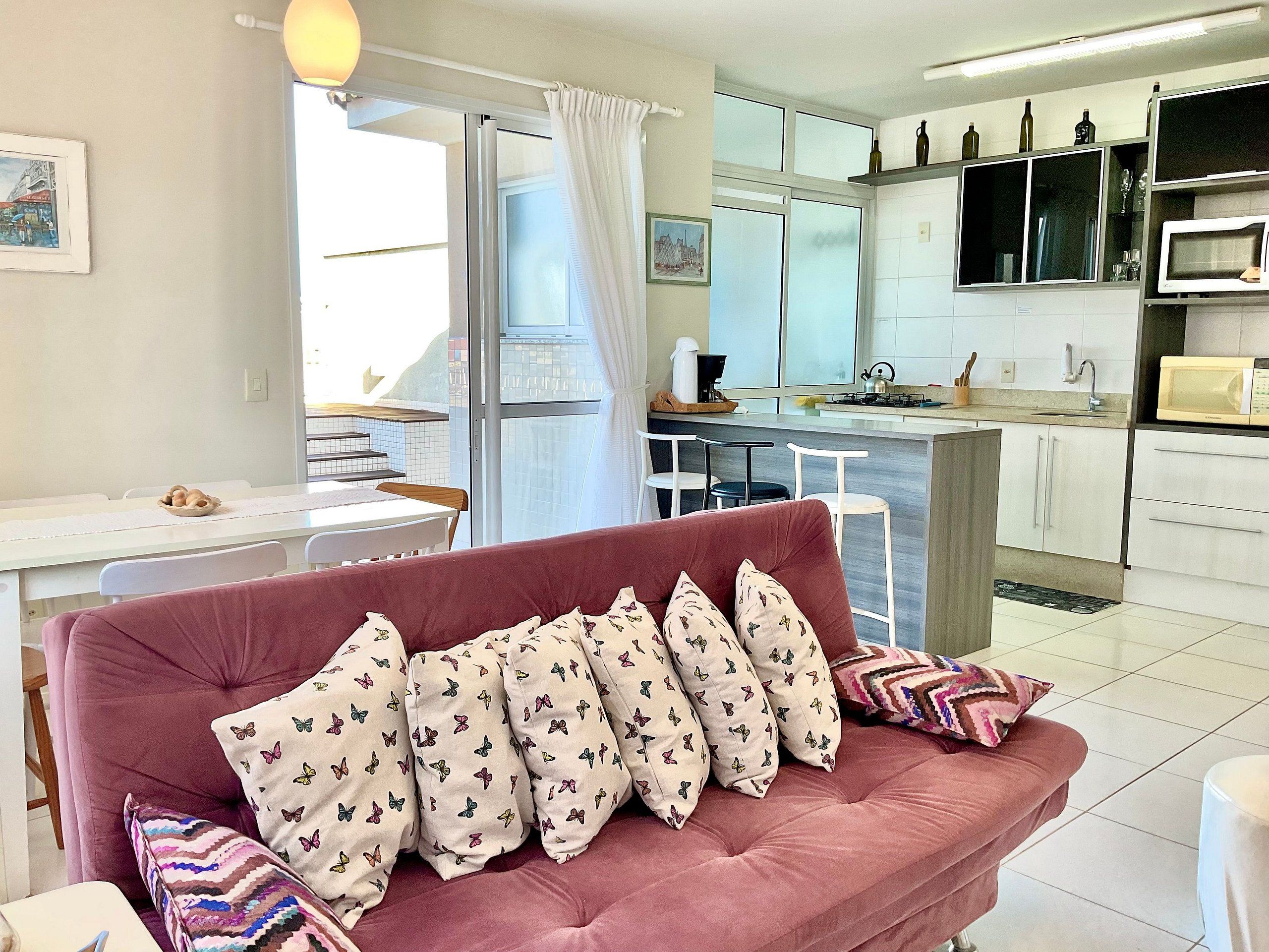 Una sala de estar con un sofá, una mesa de comedor y una cocina con microondas y armarios.