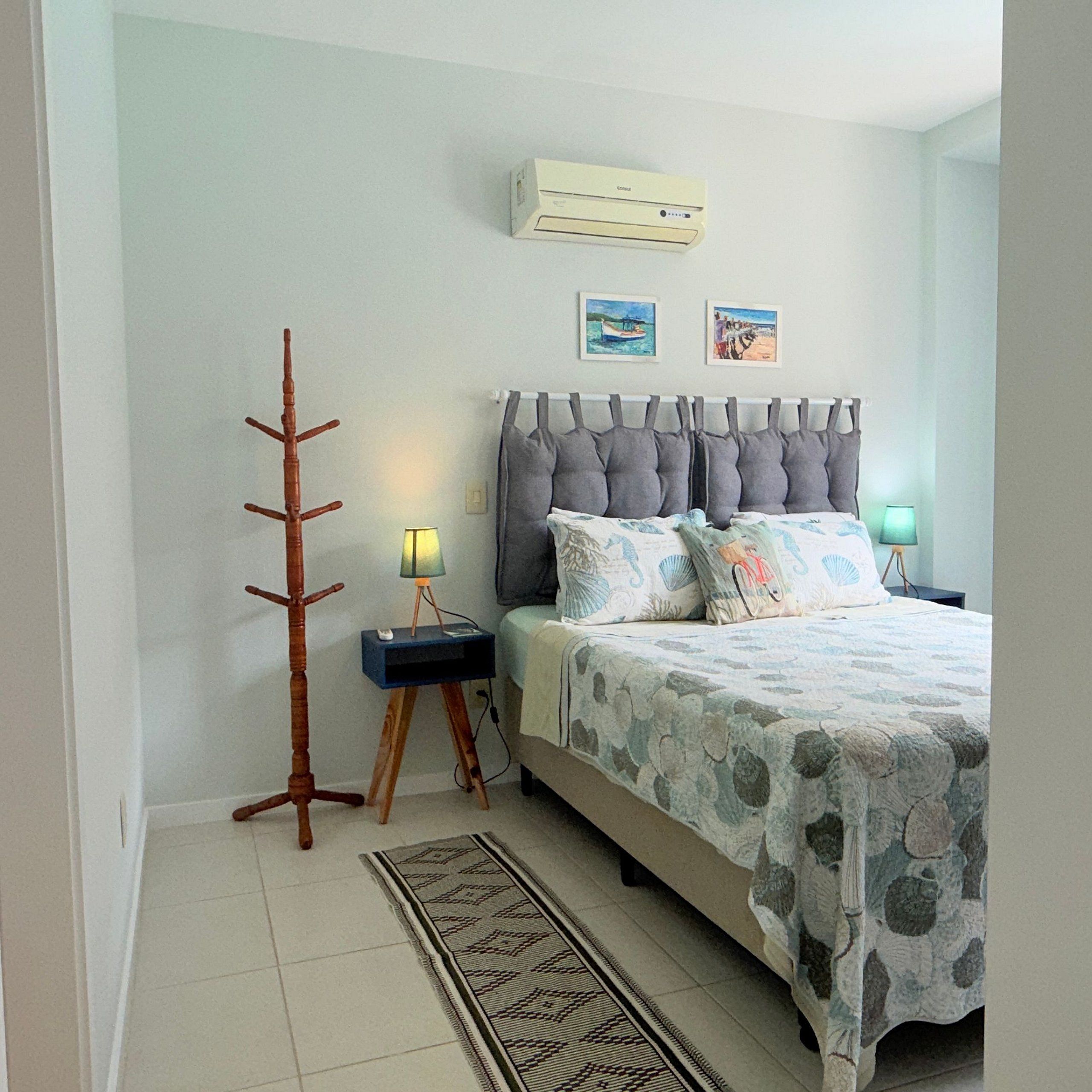 A bedroom with a bed, nightstands, a lamp, a floor lamp, a rug, and wall art.