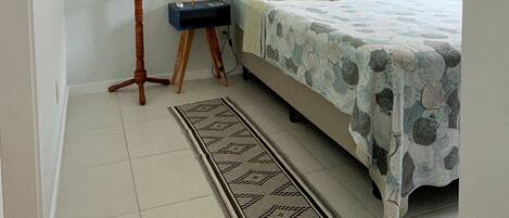 Un dormitorio con cama, mesitas de noche, lámpara, lámpara de pie, alfombra y decoración en la pared.