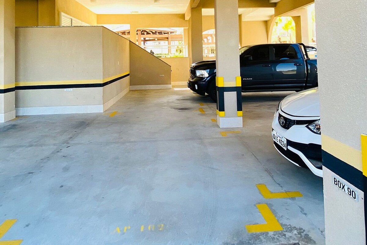 A parking garage with concrete floors, marked parking spaces, and a white car parked in one.
