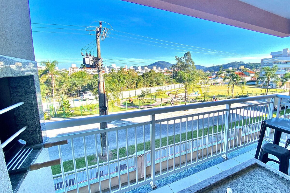 A balcony with a view of a park, a road, and buildings.