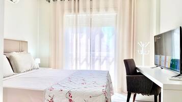 Habitación de hotel con cama, escritorio con televisor y ventana con cortinas.