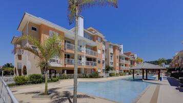 Un hotel de varios pisos con balcones, piscina y palmeras.