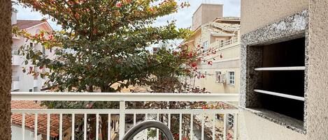 A balcony with a view of a tree and buildings.