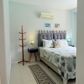 A bedroom with a bed, nightstands, a lamp, a floor lamp, a rug, and wall art. - Residencial com piscina (Florianópolis)