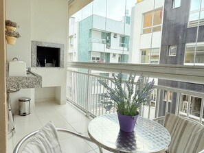 A balcony with a potted plant, a small table, and chairs.