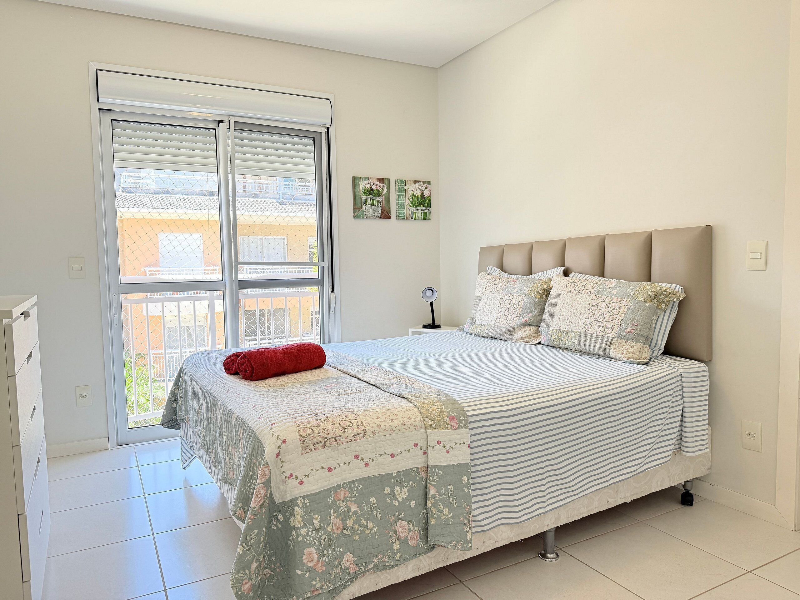 A bedroom with a bed, a window, and a view of buildings outside.