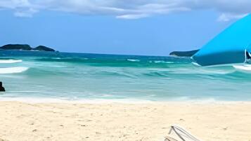 Une plage avec un hamac et une chaise de plage sur le sable.