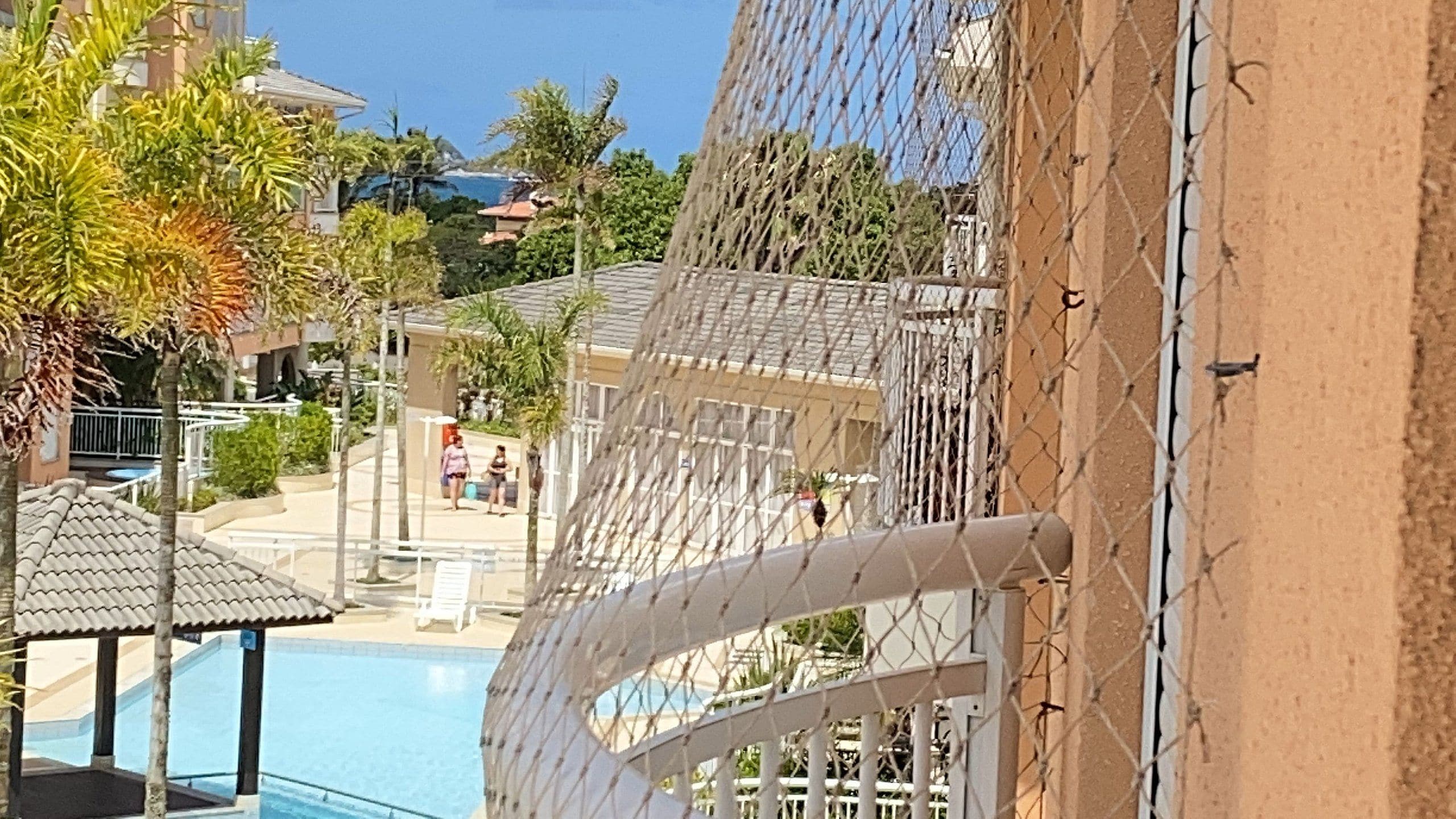 Ein Poolbereich mit Zaun, Palmen und einem Gebäude im Hintergrund.