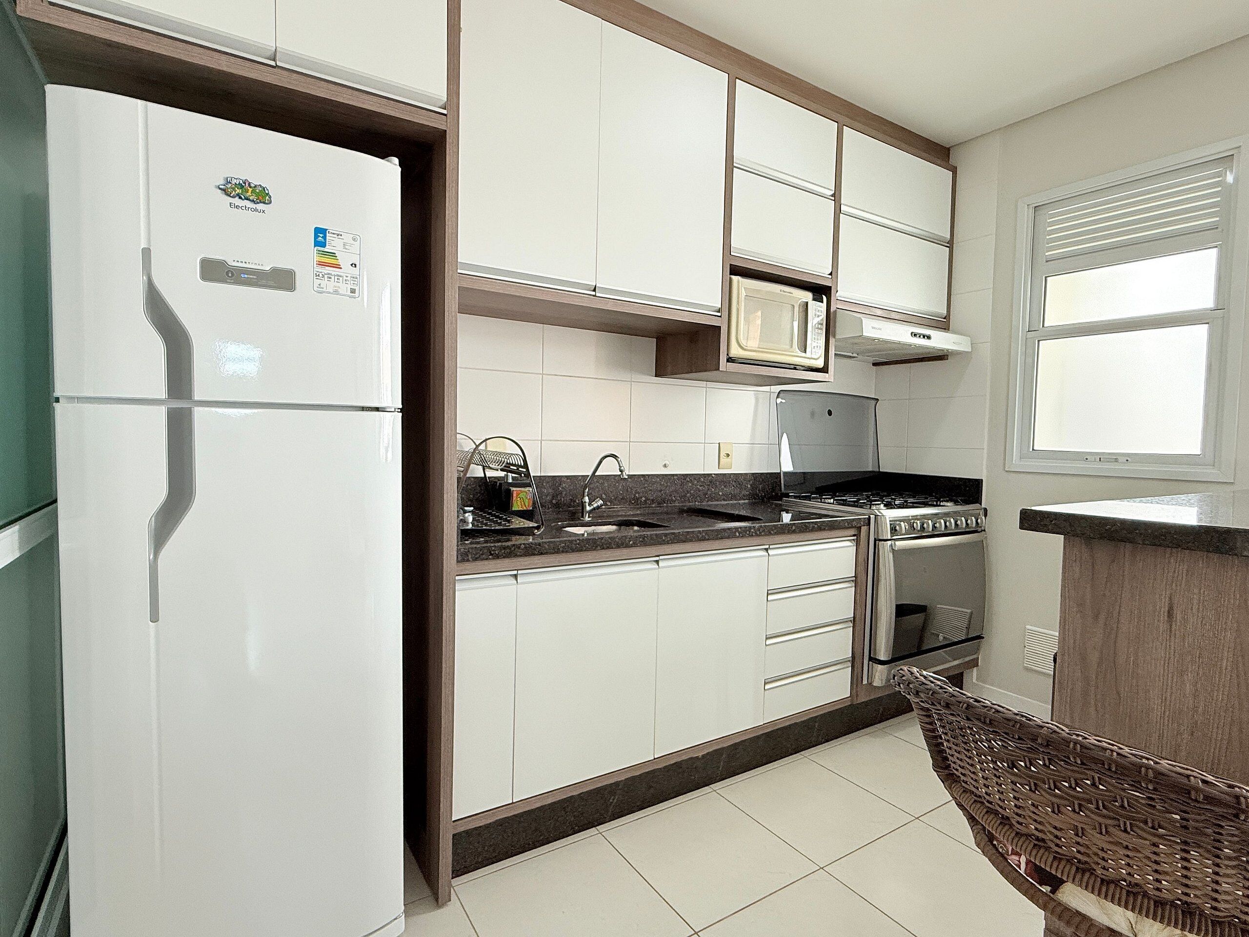 A kitchen with white cabinets, a refrigerator, a microwave, a stove, and a sink.