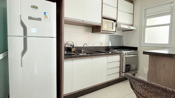 A kitchen with white cabinets, a refrigerator, a microwave, a stove, and a sink.