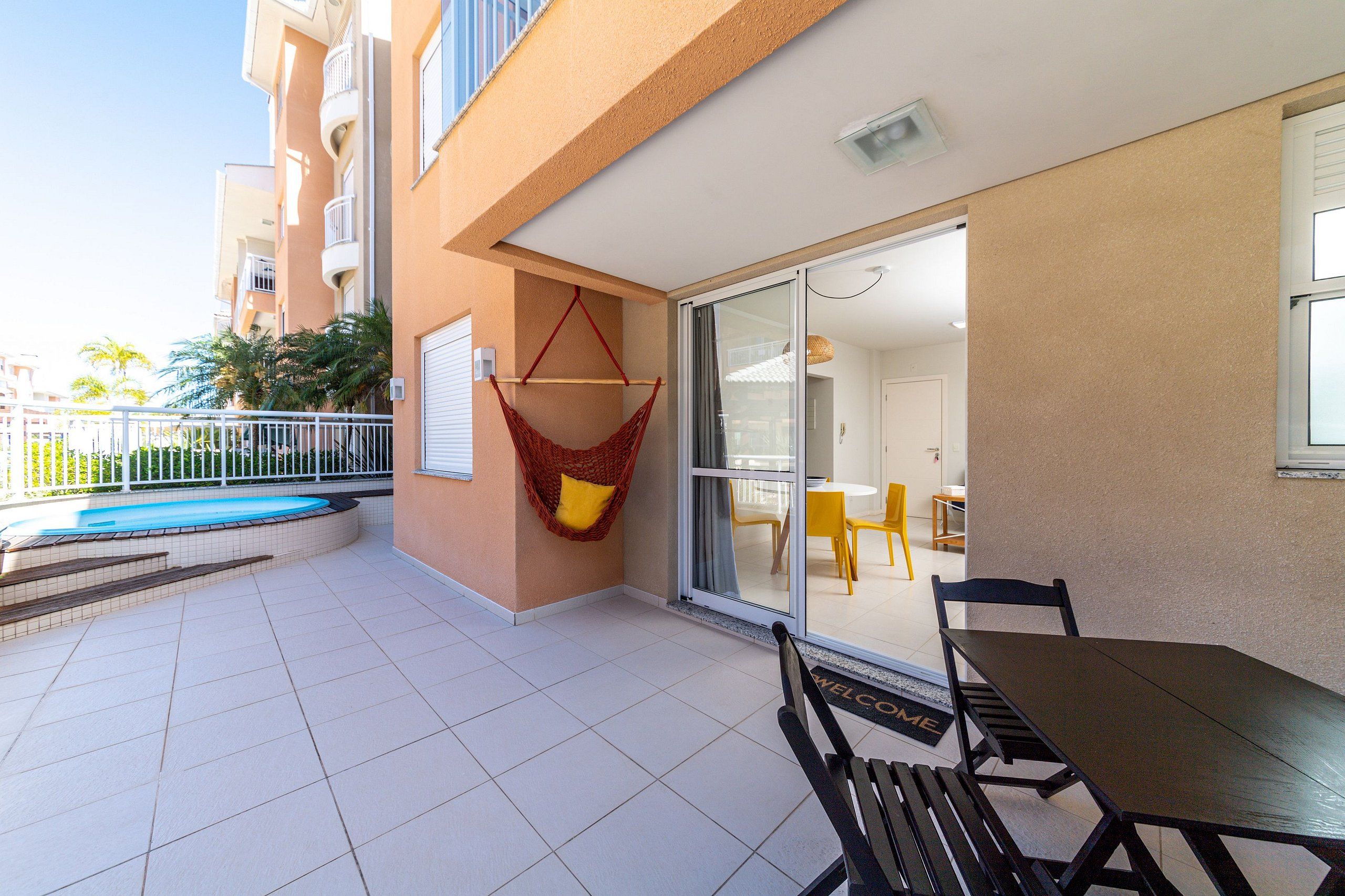 Un balcon avec une piscine, un hamac, une table et des chaises.