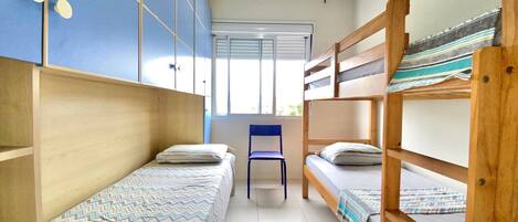 Un dormitorio con literas, una silla y una ventana.