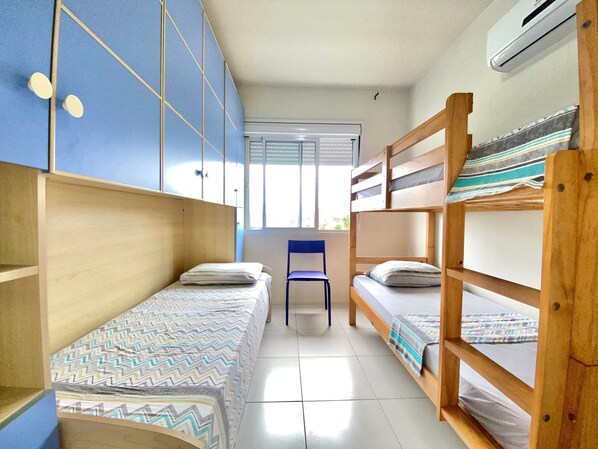 A dormitory room with bunk beds, a chair, and a window.