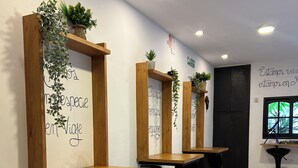 A row of wooden tables with black chairs, each with a potted plant on top. - Allpa Andina Hostel (Mendoza)