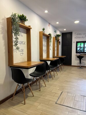 A row of wooden tables with black chairs, each with a potted plant on top. - Allpa Andina Hostel (Mendoza)