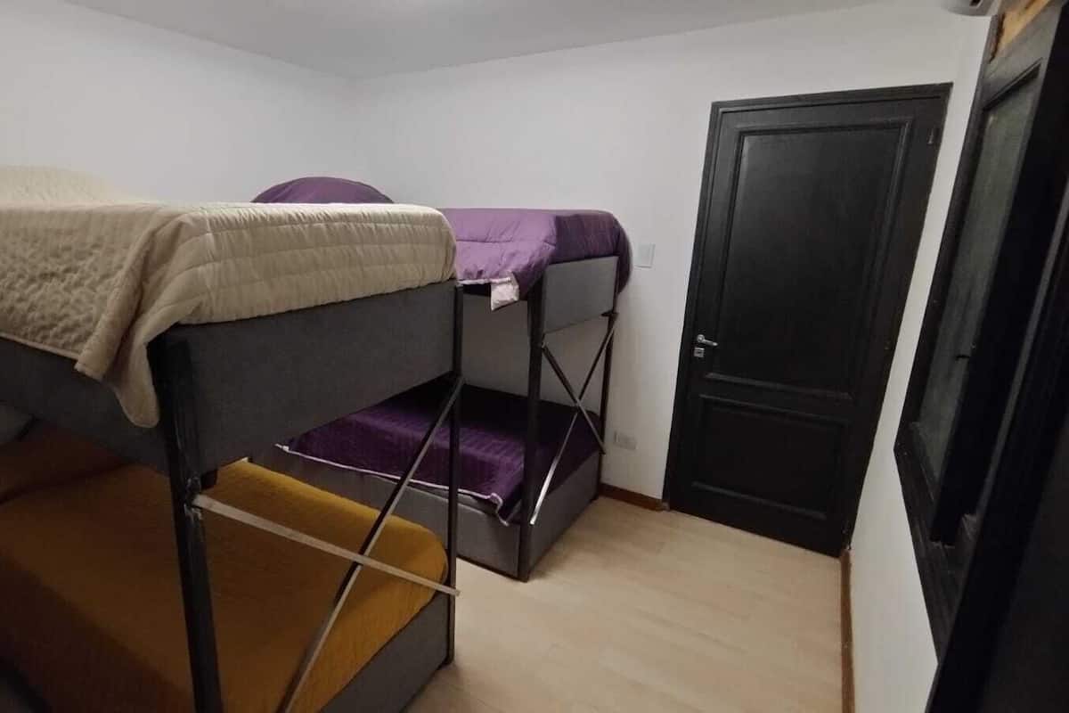 Un dormitorio con literas, una puerta y suelo de color claro.