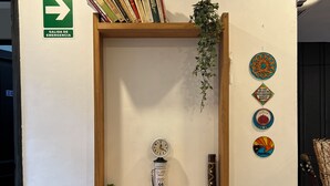 A small wooden desk with two black chairs, a clock, a plant, and decorative items on the wall. - Allpa Andina Hostel (Mendoza)