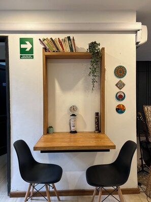 A small wooden desk with two black chairs, a clock, a plant, and decorative items on the wall. - Allpa Andina Hostel (Mendoza)