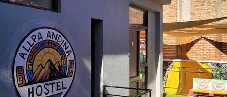 Un hostal con un logotipo circular, un balcón y una escalera.