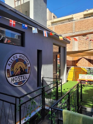 A hostel with a circular logo, a balcony, and a staircase. - Allpa Andina Hostel (Mendoza)
