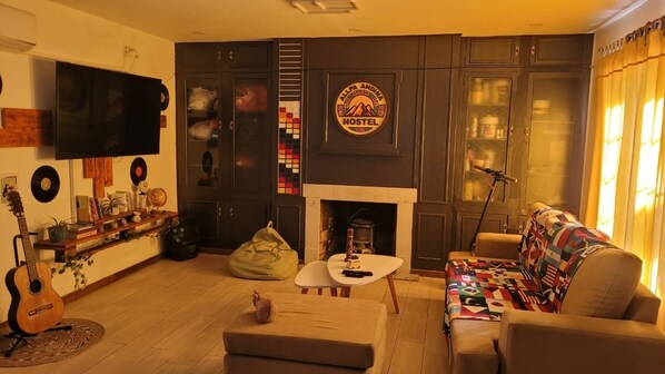 Una sala de estar con chimenea, televisor, sofá, mesa de centro y una guitarra.
