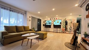 A living room with a sofa, a coffee table, a TV, and a bar area with stools. - Allpa Andina Hostel (Mendoza)
