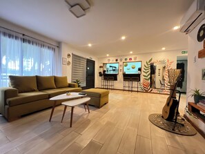A living room with a sofa, a coffee table, a TV, and a bar area with stools. - Allpa Andina Hostel (Mendoza)