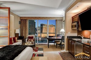 Ein Hotelzimmer mit Balkon, Essbereich, Küche und Blick auf die Stadt.