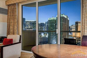 Ein Hotelzimmer mit einer großen Schiebeglasdoor, einem Esstisch, einer Couch und einem roten Kissen.