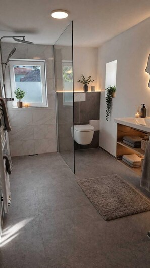 A modern bathroom with a glass shower enclosure, a toilet, a sink with a mirror, and a small window.