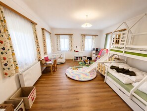 Une chambre d’enfant avec des lits superposés, un espace de jeux et un bureau avec des jouets.