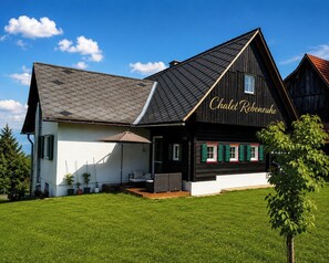 A chalet with a dark roof, a white facade, and green shutters.