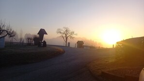 Una carretera serpenteando por una zona rural, con un amanecer o atardecer al fondo.