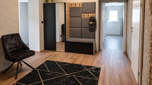 Un interior moderno con una butaca tapizada de negro, un felpudo negro y dorado de diseño geométrico, una zona de estar con un banco y un techo de madera.